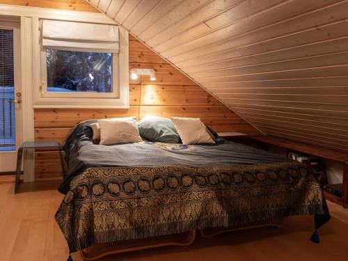 a bed in a wooden room with a window at Mäntypirtti Log Villa in Rovaniemi