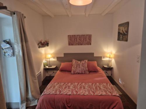 a bedroom with a bed with red sheets and two lamps at A La Maison in Les Repôts