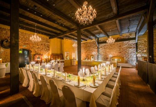 a large room with a long table with white chairs at Hotel Wellness Goldenes Fass Meißen in Meißen