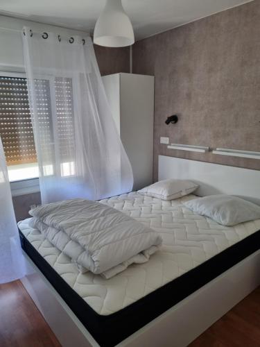 a white bed in a room with a window at Appartement 30 m de la mer in La Turballe