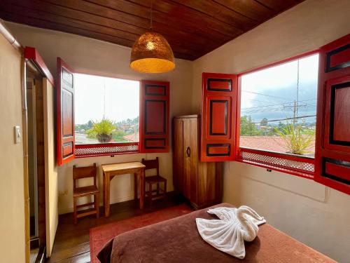 a room with red windows and a bed and a table at Hostal Tralala Salento in Salento