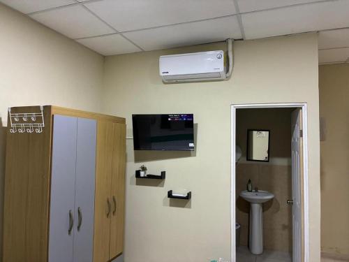 a room with a bathroom with a tv and a sink at Nómada San Miguel in Colonia Milagro de La Paz