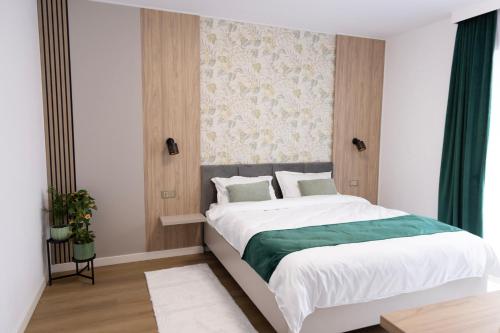 a bedroom with a large bed with white sheets and green blanket at Mira Montis in Borşa