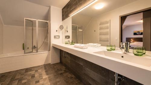 a bathroom with a sink and a shower and a mirror at Béni golf club Clervaux hôtel & Restaurant in Eselborn