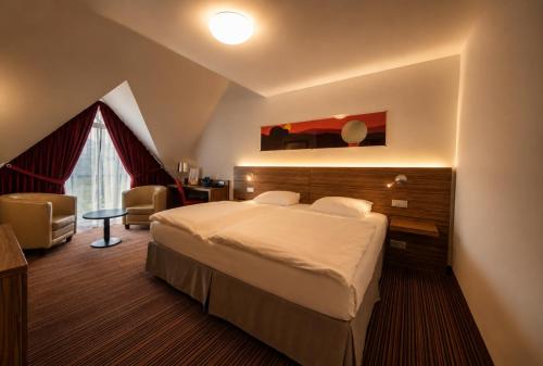 a hotel room with a large bed and a desk at Béni golf club Clervaux hôtel & Restaurant in Eselborn