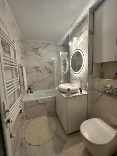 a white bathroom with a toilet and a sink at Elite Apartaments in Curtea de Argeş
