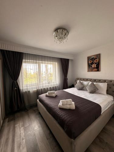 a bedroom with a large bed with two towels on it at Elite Apartaments in Curtea de Argeş