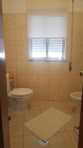 a bathroom with a toilet and a sink and a window at Moradia Vinhais in Vinhais
