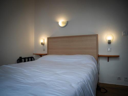 a bedroom with a white bed and two lights on the wall at Hotel BETHEL in Nevers