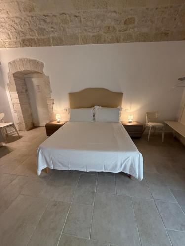 a bedroom with a white bed with two tables and chairs at Neptune Stone House in Molfetta