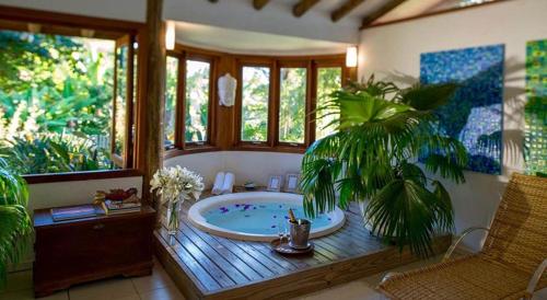 a bathroom with a jacuzzi tub with a palm tree at Pousada Quinta do Bucanero in Imbituba