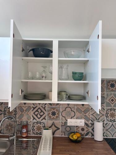 a kitchen cabinet with plates and bowls in it at Le nid d'Eve - studio cosy près de Strasbourg avec piscine in Illkirch-Graffenstaden