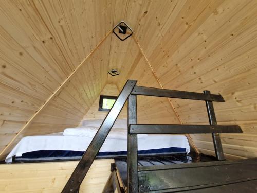 ein Bett in einer Holzhütte mit Fenster in der Unterkunft Haiduk Aframe in Brebu