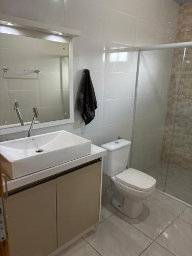 a bathroom with a sink and a toilet and a mirror at Sitio em São Pedro de Alcantara in São Pedro de Alcântara