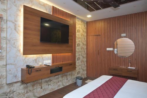 a bedroom with a bed and a television on the wall at Winners Hill Resort Walayar by Arcadia in Coimbatore