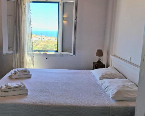 a bedroom with a bed with a window and two towels at Paraga Meltemi View in Platis Gialos
