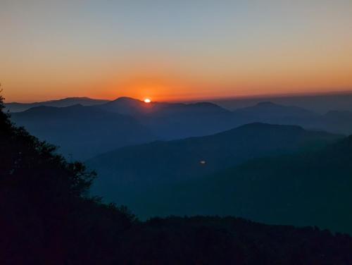 a sunset over a mountain range with the sun setting at Mochilero B&B in Darjeeling