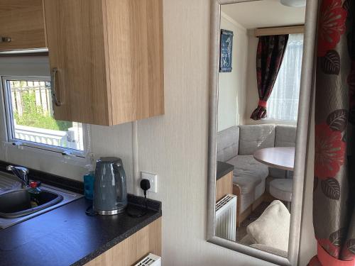a kitchen with a sink and a mirror in a caravan at Cosy Costal Escape in Westward Ho