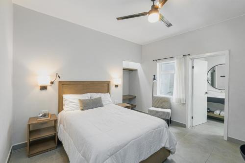 a white bedroom with a bed and a chair at Casa Othir in Monterrey