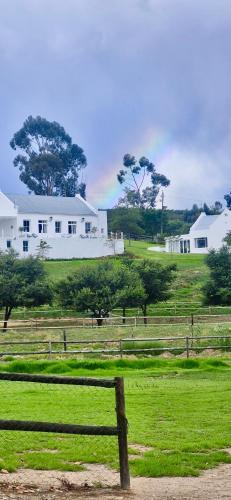 a field with a fence and a white house at Firgrove Country House in Robertson