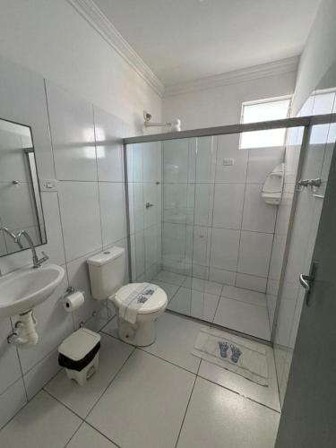 a white bathroom with a toilet and a sink at Pousada Maceió é Massa Beira Mar in Maceió