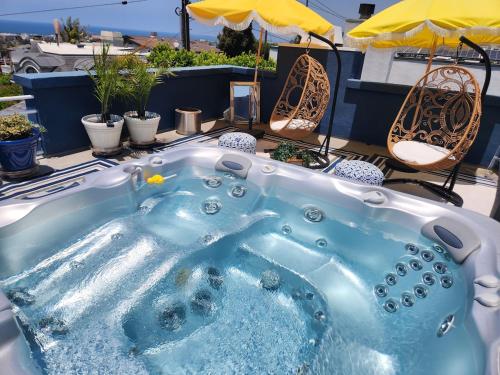 a hot tub on a patio with chairs and an umbrella at Luxury Spa Townhome with Rooftop Ocean View Jacuzzi in Hermosa Beach