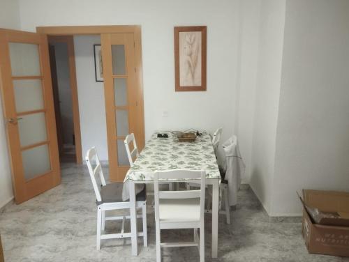 a dining room with a table and white chairs at Zapillo 2&1 in Almería