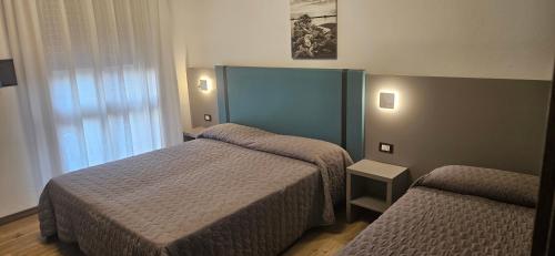 a hotel room with two beds and a window at Hotel Sole in Eraclea Mare
