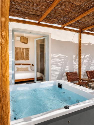a large bath tub in a room with a bedroom at Kyma Sunset Suite w Prvate Jacuzzi in Paros National Airport