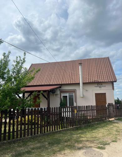 a small white house with a wooden fence at Éva Vendégház in Hajdúnánás