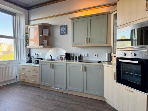 a kitchen with white cabinets and a large window at Longsands Beach, Apartment 2, Tynemouth in Tynemouth