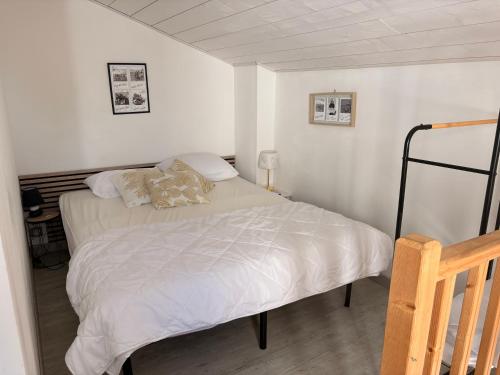 a bedroom with a bed with white sheets and pillows at Maisonnette Oléron à 30 mètres de la plage 3 étoiles in Saint-Denis-dʼOléron