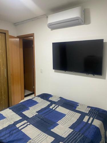 a bedroom with a bed and a tv on the wall at Apto 2Q com Area de Lazer e Piscina in São Gonçalo do Amarante