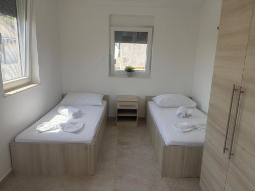 two beds in a small room with a window at Apartmani Maleš in Rogoznica
