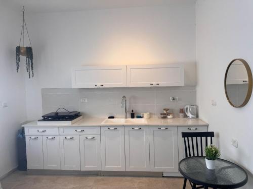 a kitchen with white cabinets and a table and a mirror at קסם צפתי in Safed