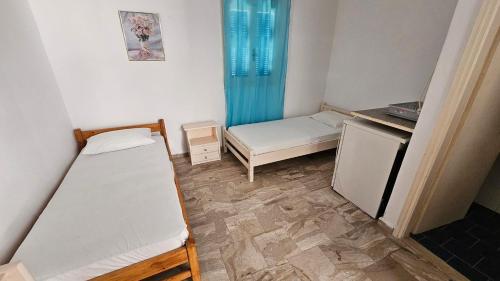 a small room with two beds and a refrigerator at Small Apartments Rooms Only in Perissa