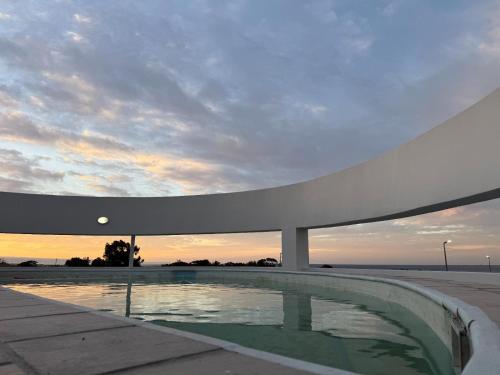 a building with a pool in front of a sunset at St Helena Bay Hotel in St. Helena Bay