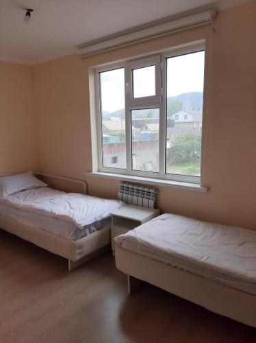 two beds in a room with a window at Guest House South Wind in Pokrovka