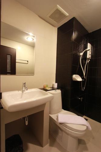 a bathroom with a white toilet and a sink at Trendy Hotel in Nakhon Pathom
