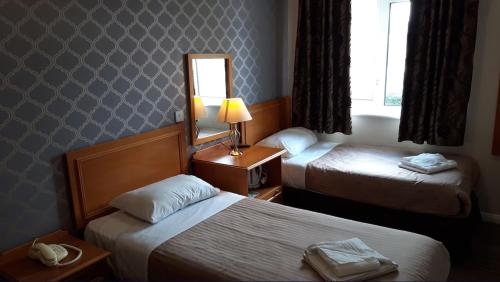 a hotel room with two beds and a mirror at The Durley Chine Hotel in Bournemouth