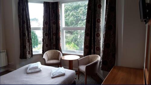 a room with a bed and chairs and a window at The Durley Chine Hotel in Bournemouth