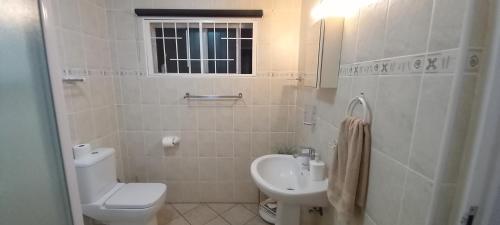 a white bathroom with a toilet and a sink at Sand And Sea Self Catering #3 in Swakopmund