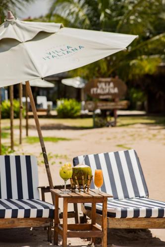 two chairs and a table with an umbrella at Pousada de Charme Villa Italiana - Pé na Areia in São Miguel dos Milagres