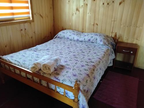 a bed in a wooden room with towels on it at Cabañas almendra in Quellón