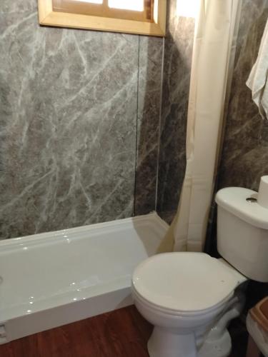 a bathroom with a toilet and a tub and a sink at Cabañas almendra in Quellón