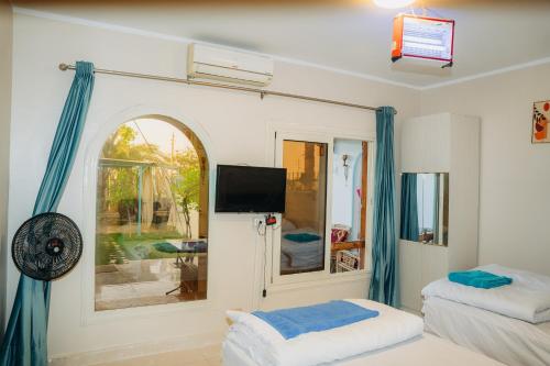 a room with two beds and a tv on the wall at Tranquil Villa, private Pool, Garden, Wifi, Fayoum in Qaryat at Ta‘mīr as Siyāḩīyah