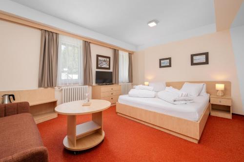 a hotel room with a bed and a table at Horský Hotel Jelínek in Bedřichov