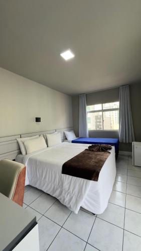 a bedroom with a large bed and a window at Hotel Gênova BC in Balneário Camboriú