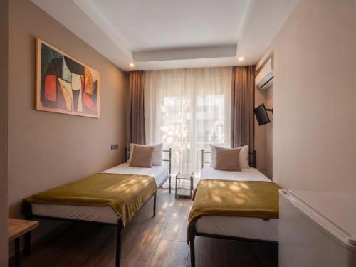 two beds in a room with a window at Köşk Boutique Hotel - Old Town & City Center in Antalya