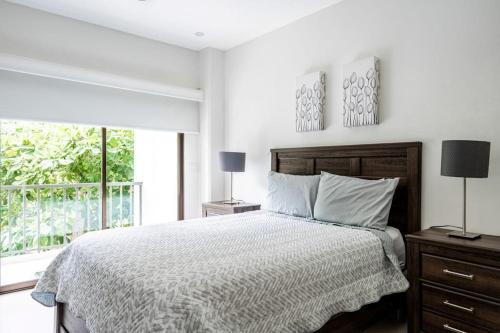a white bedroom with a bed and a window at Jaco Bay 1202 in Jacó